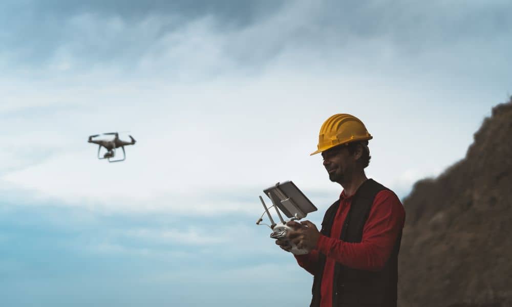 Surveyor Using Drone for LiDAR Mapping in Rugged Terrain - ALTA SURVEY Denver urveyor operating drone for LiDAR mapping near hillside terrain, showing modern tools used in elevation and surface surveys.