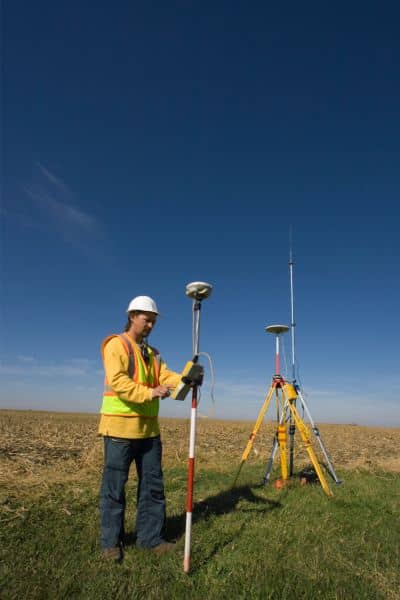 Surveyor using GPS equipment for a modern boundary survey on open land in Denver