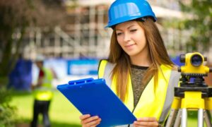 Denver construction management with land surveying equipment - ALTA SURVEY Denver Construction management professional in safety vest and hard hat reviewing plans beside land surveying equipment on a Denver job site