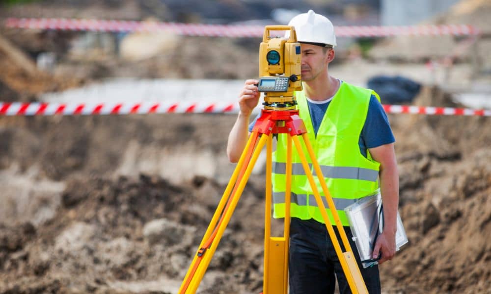Land surveyor using a total station during a topographic survey on a construction site in Denver
