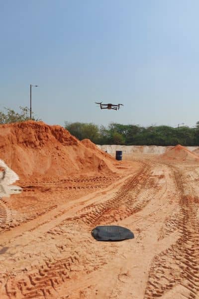 Drone conducting a construction survey over a roadway site for mapping and elevation checks
