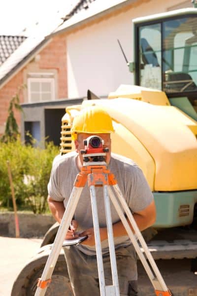  Licensed land surveyor using GPS equipment to mark precise property boundaries in an urban area.
