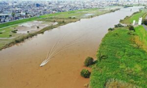 Aerial view of a flooded riverbank near urban properties showing why an ALTA survey is essential after extreme weather events.