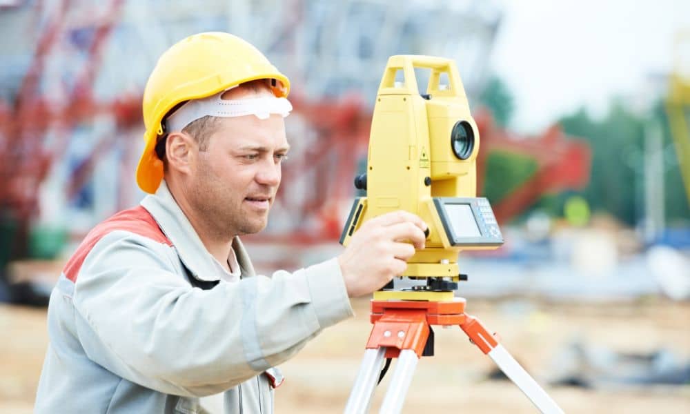 A construction surveyor using precision equipment on an active construction site