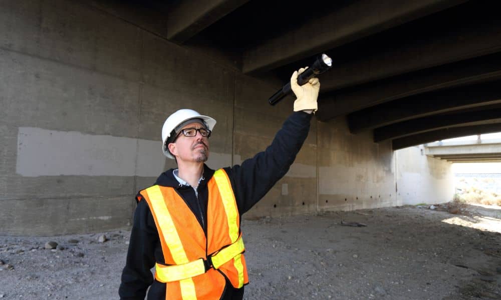 Structural engineer inspecting the underside of a concrete bridge during a safety evaluation