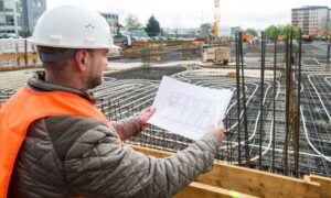 Construction site plan review - ALTA SURVEY Denver Builder reviewing land development plans at an active urban construction site