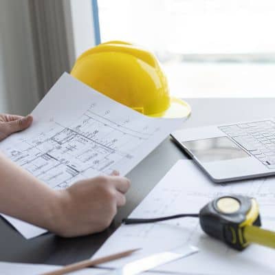 Structural engineer reviewing construction drawings and load calculations at a desk