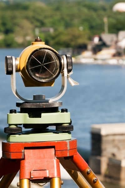 Land survey equipment measuring elevation - ALTA SURVEY Denver Survey equipment measuring property elevation for an elevation certificate near a water area